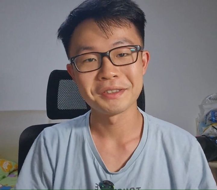 Chuan Long at his desk, speaking to the camera